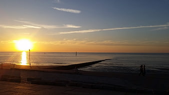 Silhouettes of people walking on beach at golden sunset