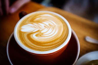 Close-up of latte art in a white ceramic cup on a wooden table