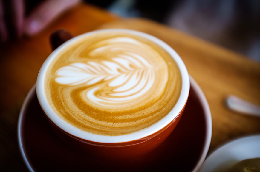 Close-up of latte art in a white ceramic cup on a wooden table
