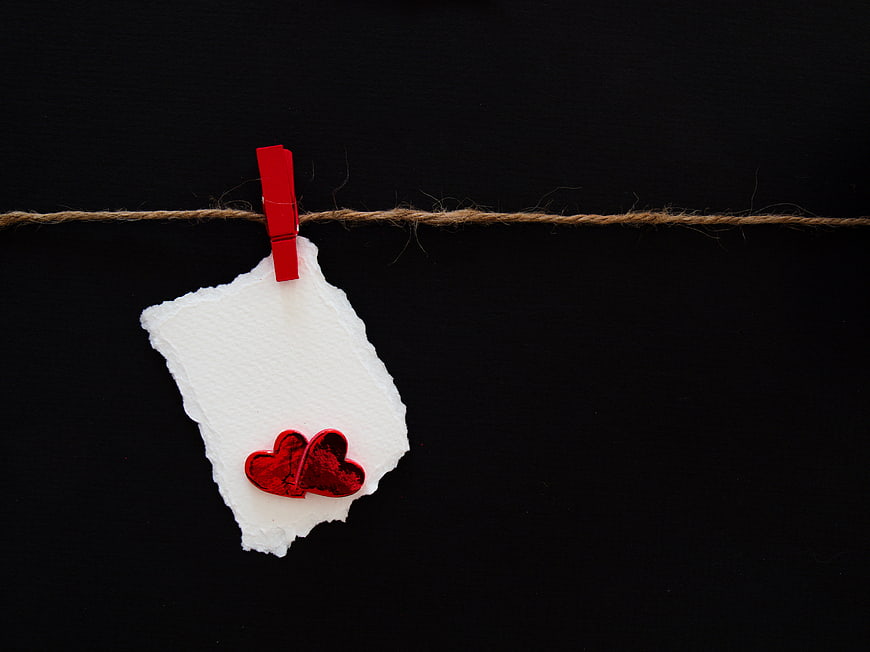 Red heart on torn paper note hanging on twine