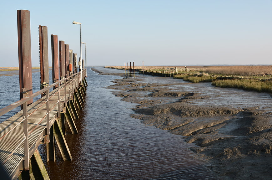 Metal pier extending over tidal mudflats at low tide