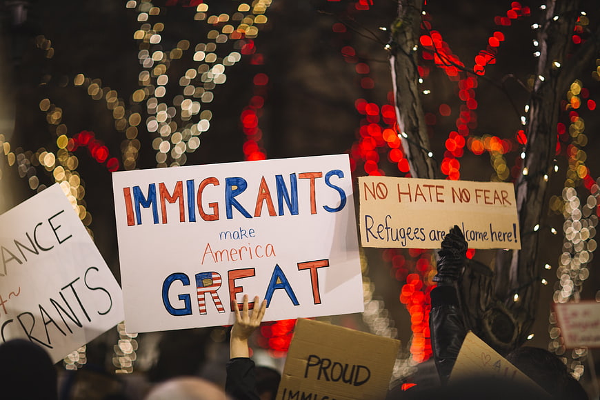 Protest signs supporting immigrants at night rally with bokeh lights