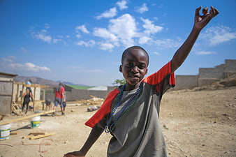Young African boy raising hand at construction site