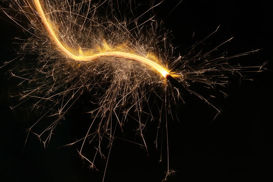 Golden Sparkler Sparks Bursting Against Black Background
