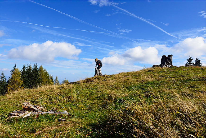 Young girl hiking on grassy mountain ridge with blue sky