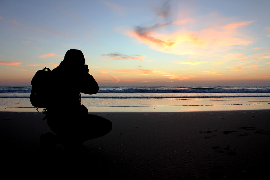 Silhouette of Photographer Taking Photo on Beach at Sunset