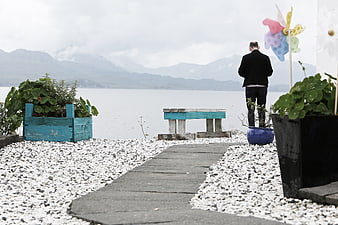 Man Standing by Lake Path with Mountains