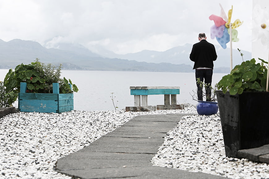 Man Standing by Lake Path with Mountains