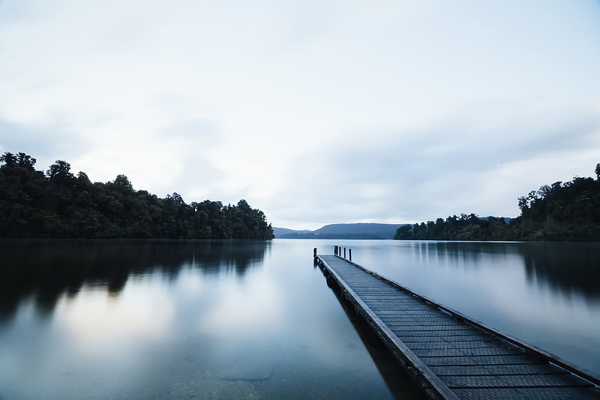 Serene Wooden Dock on Calm Lake with Forest Reflections