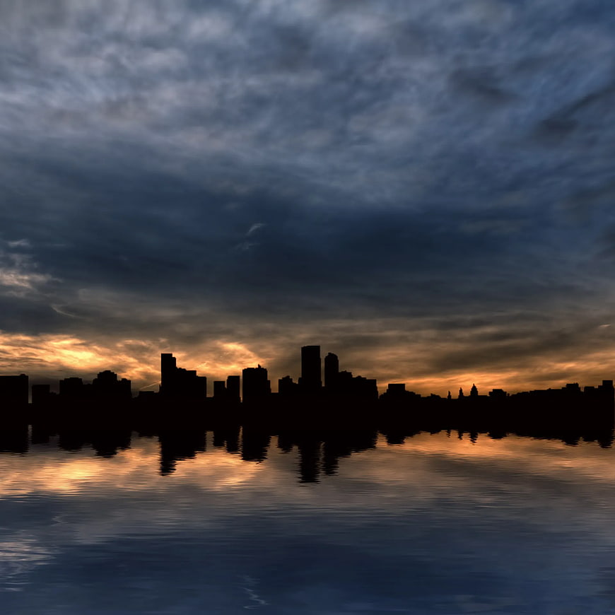 Dramatic city skyline silhouette at sunset with water reflection