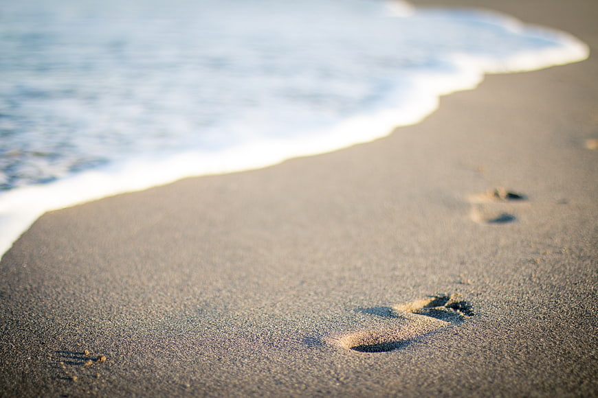 Footprints in Sand on Beach Shore with Ocean Waves