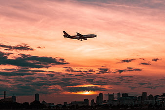 Airplane Landing Against Vibrant Sunset Skyline