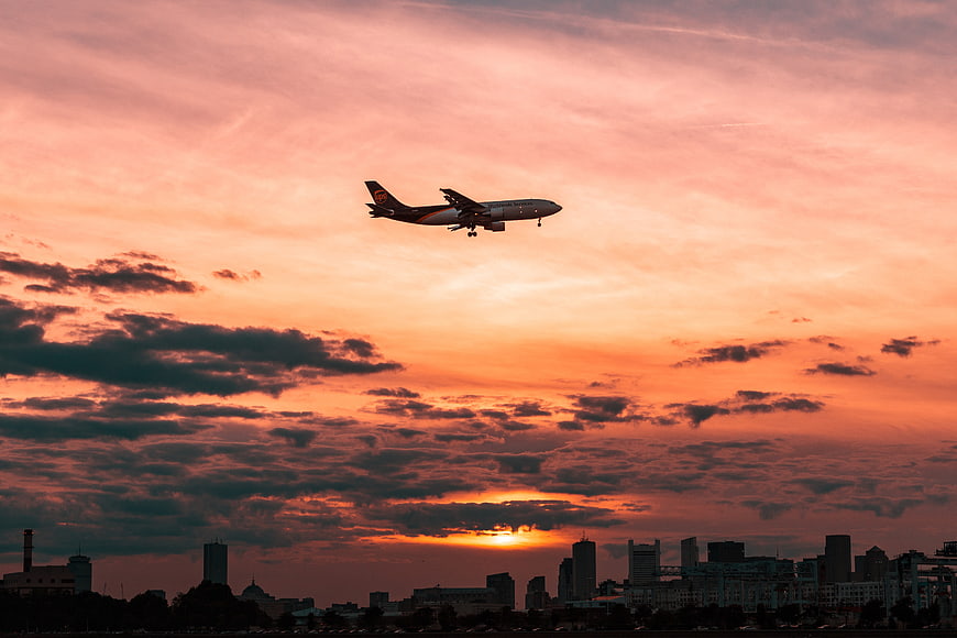 Airplane Landing Against Vibrant Sunset Skyline