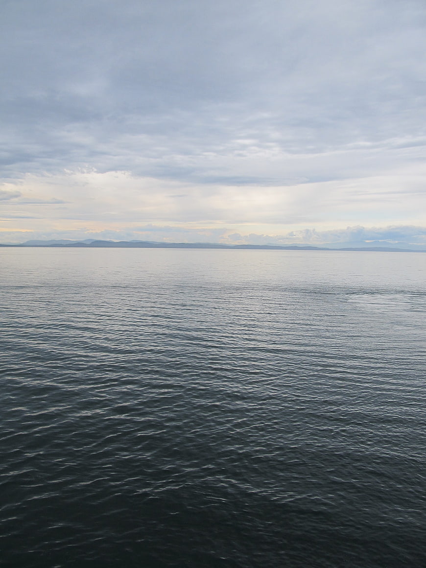 Calm Ocean View with Distant Mountains and Cloudy Sky