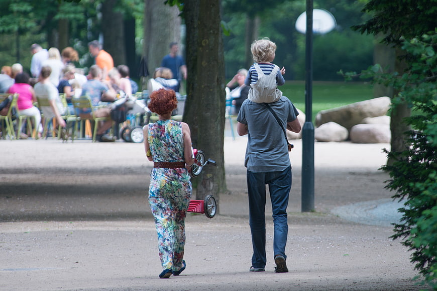 Family walking away in park with child on shoulders