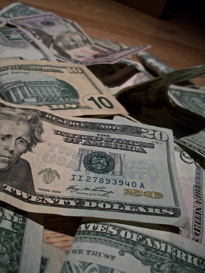 Scattered US Dollar Bills on Wooden Surface
