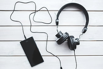 Black headphones and smartphone on white wooden background