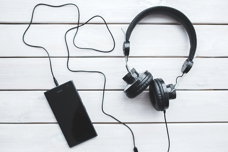 Black headphones and smartphone on white wooden background
