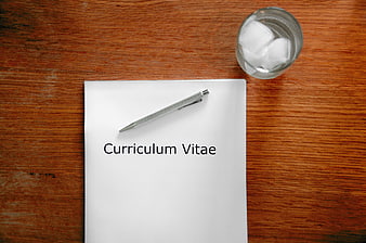 Curriculum Vitae Document on Wooden Desk with Pen and Water
