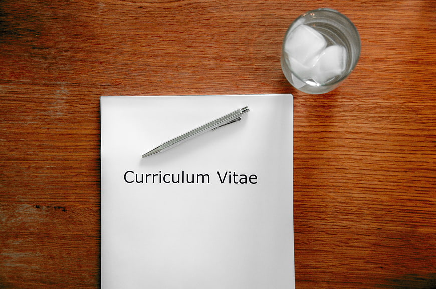 Curriculum Vitae Document on Wooden Desk with Pen and Water