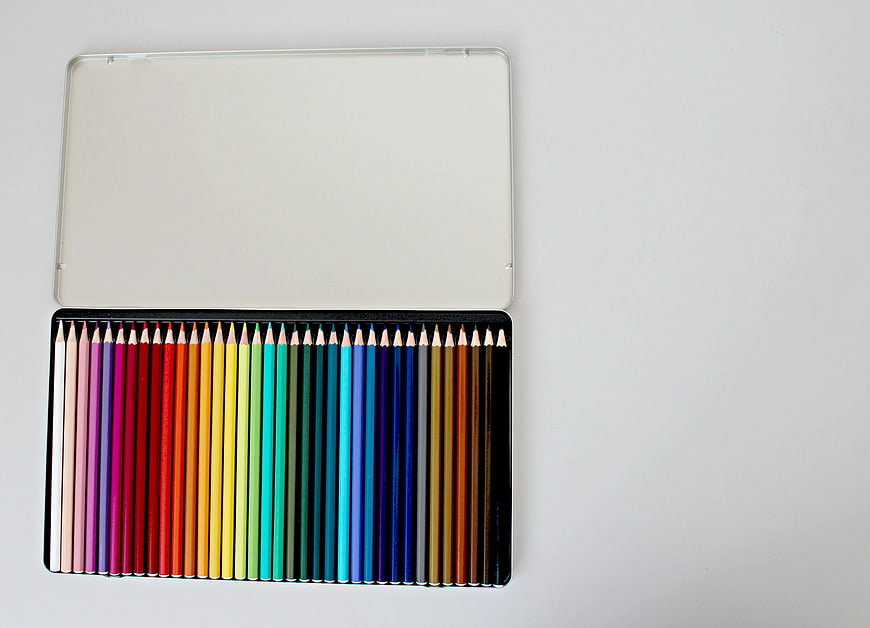 Open Tin of Assorted Color Pencils on White Background