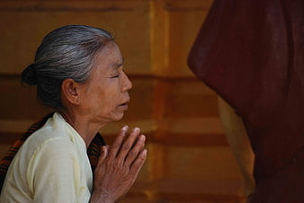 Senior Asian Woman Praying In Profile With Hands Together