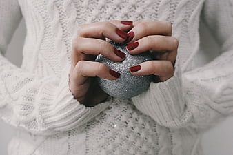Woman Holding Silver Christmas Ornament in White Sweater