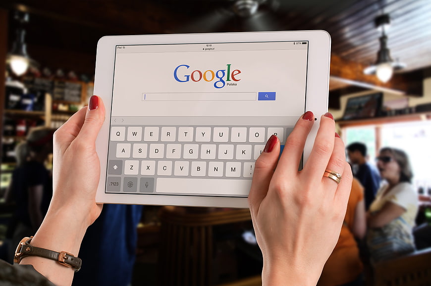 Hands holding tablet with Google search page in cafe
