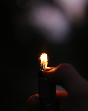 Hand holding lit lighter in dark night setting