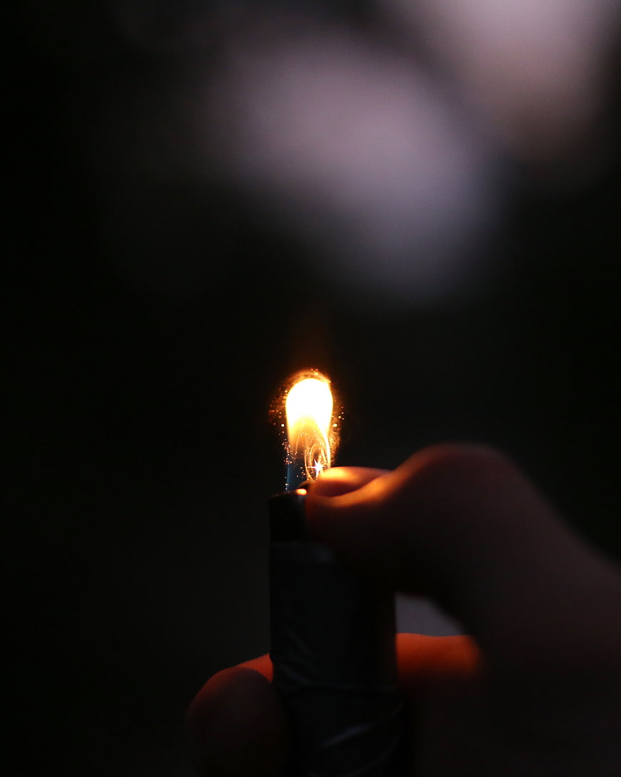 Hand holding lit lighter in dark night setting