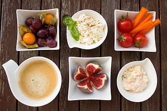 Healthy breakfast spread with coffee, fruit, and vegetables on wood