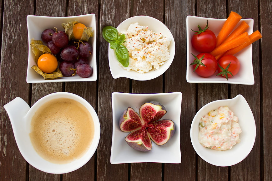Healthy breakfast spread with coffee, fruit, and vegetables on wood