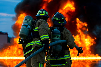 Two Firefighters Facing Large Fire with Hose