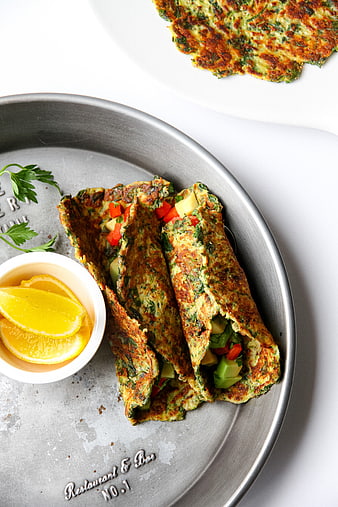 Overhead view of savory vegetable omelet tacos with lemon wedges