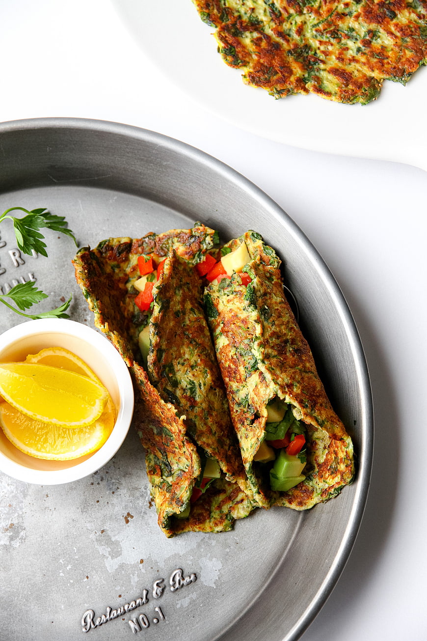 Overhead view of savory vegetable omelet tacos with lemon wedges