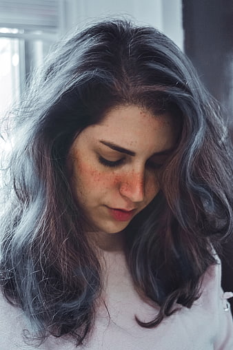 Close-up portrait of a young woman with freckles looking down