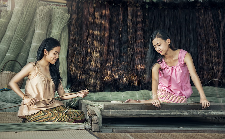 Two Young Women Weaving Traditional Textiles on a Wooden Loom