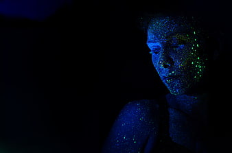 Woman with Glowing Blue and Green Body Paint in Dark Setting