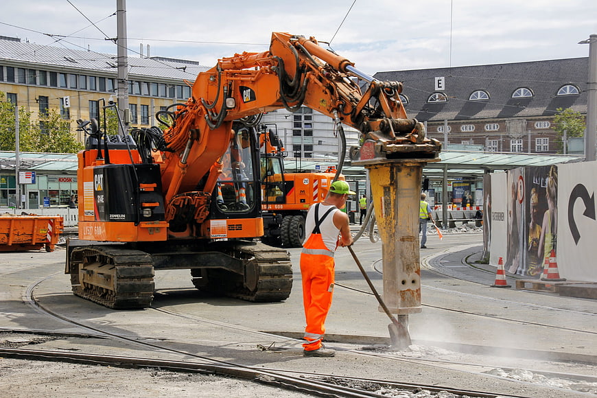 Construction worker operating heavy machinery at urban tram site