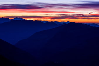 Vibrant Sunset Over Layered Mountain Silhouettes