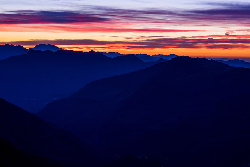 Vibrant Sunset Over Layered Mountain Silhouettes