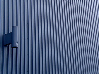 Blue corrugated metal wall with industrial vent pipe