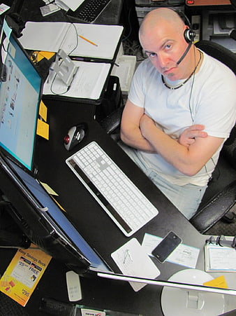 Man with headset at cluttered office desk