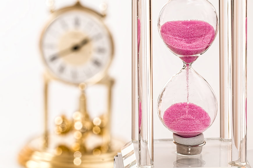 Pink hourglass with vintage clock measuring time