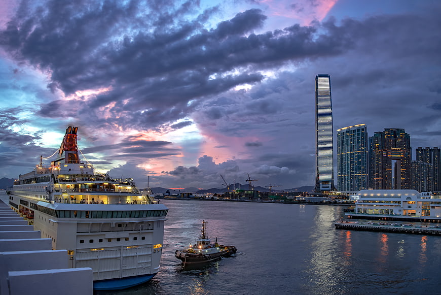Cruise ship docked in Hong Kong harbor at twilight with skyline