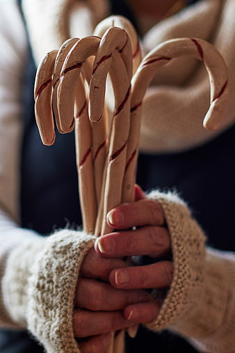 Hands holding handmade peppermint candy canes in cozy sweater