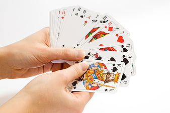 Hands holding a fan of playing cards on white background