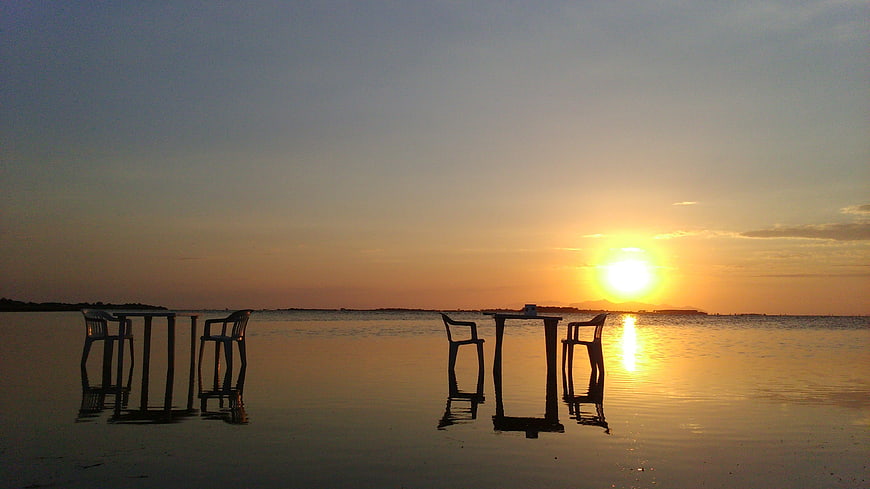 Silhouetted Beach Chairs and Table at Sunset