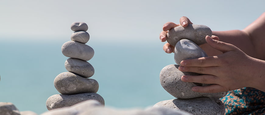 Hands stacking stones for zen balance by the sea