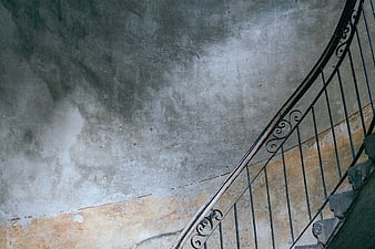 Vintage spiral staircase with wrought iron railing against textured wall